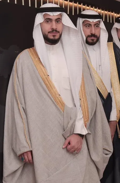 Man wearing a light grey bisht with gold zari