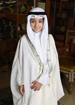 Boy smiling in a cream bisht with dark and gold edging