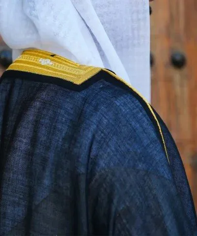Back view of a black bisht with a gold zari collar